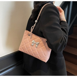 Detail of pink quilted shoulder bag with silver bow and leather-intertwined chain strap