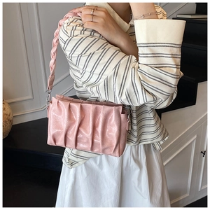 Detail of pink pleated crossbody bag with thick woven shoulder strap and silver hardware