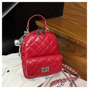 Detail of red quilted mini backpack with silver chain strap and metal ball charm decoration