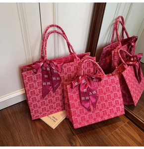 Detail of pink bridal tote bags featuring red Xi characters and satin bow decorations