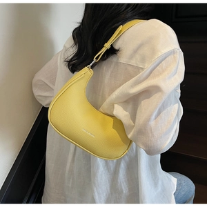 Detail view of yellow crescent shoulder bag in pebble leather worn by a model