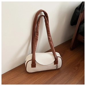 Dettaglio borsa a bauletto in tela beige con finiture in pelle marrone e ciondolo in metallo