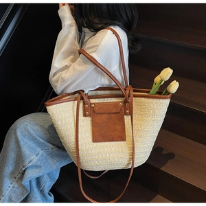 Straw tote bag with brown leather trim held by a model on stairs for a beach vacation look