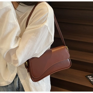 Vue détaillée du sac bandoulière en cuir marron avec rabat ondulé et boucle dorée