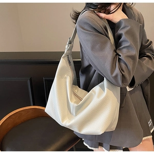 Detail view of the white pebble leather hobo bag showing texture and wide strap on model