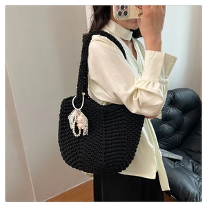 Detail of black hand-woven tote bag with lace pearl charm and lamb doll accessory