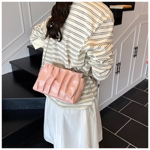 Detail of pink pleated cloud bag with metallic silver chain strap on model