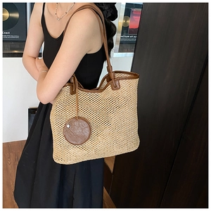Close-up of woven straw tote bag with brown leather handles in a retro lifestyle setting