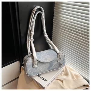 Dettaglio borsa boston in denim sfumato blu con manici argento e chiusura lampo