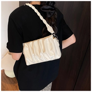 Detail of creamy white ruched cloud bag featuring braided strap and silver hardware