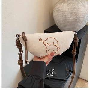 Détail de broderie chiot sur sac demi-lune en toile beige avec bandoulière à nœuds