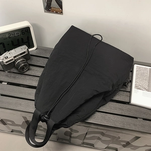 Detail einer schwarzen Nylon-Tasche auf grauem Holztisch mit Retro-Kamera-Deko