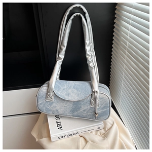 Dettaglio della trama in denim blu e bordo argento su una borsa a spalla di design