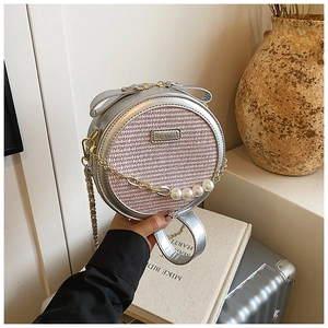 Detail of silver round crossbody bag featuring pink woven texture and pearl chain strap