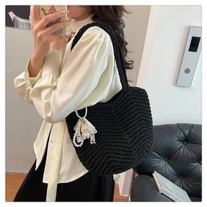 Detail of hand-woven black tote bag with pearl charms, lace ribbon and doll ornament