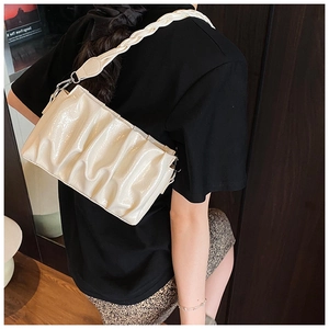 Detail of off-white pleated cloud bag with woven handle and silver metallic clasp