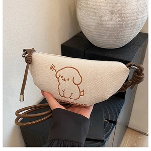 Détail de la broderie chiot sur le sac bandoulière croissant en toile beige