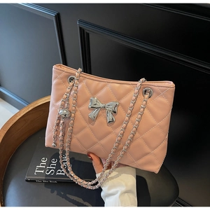 Close-up of pink quilted chain bag featuring a silver bow accent and fine stitching
