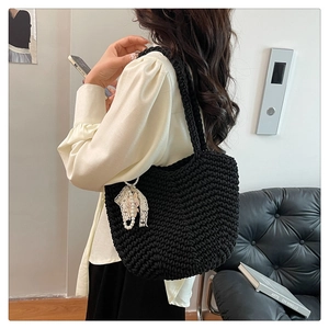 Detail of black hand-woven shoulder bag featuring crochet texture and pearl charm