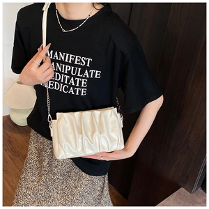 Detailed view of the pleated cloud bag with metallic chain strap worn by a model