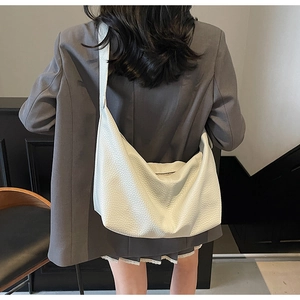 Detail of white dumpling crossbody bag with premium lychee grain texture and wide strap
