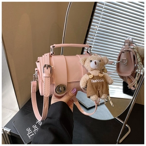 Close-up of pink patent leather handbag with a cute teddy bear charm and metal buckle