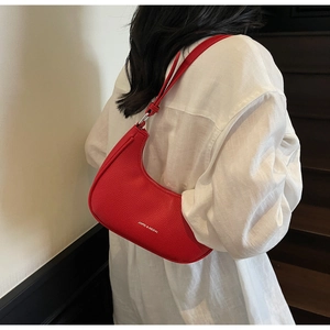 Detail of red crescent hobo bag in lychee pattern leather with branding and metal buckle