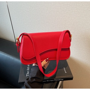 Detail view of red lychee grain leather underarm bag with elegant gold metal buckles