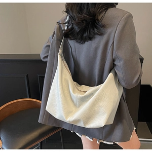 White lychee leather hobo bag worn over a grey blazer showing large capacity and soft texture