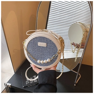 Detailed view of woven round crossbody bag with pearls and mirror reflection