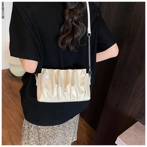 Detail of cream pleated cloud bag with leather and silver chain strap on model