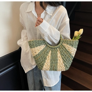 Detail of hand-woven straw bag featuring green and beige stripes with gold chain trim