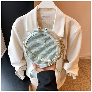 Detail of woven straw circle bag with pearl handle and mint green leather strap