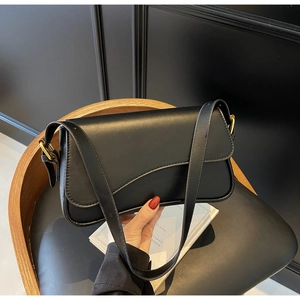 Vue détaillée du sac sous le bras noir avec boucle dorée et rabat au design incurvé