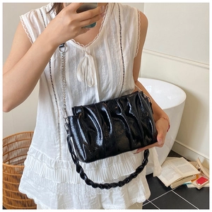 Detail of black pleated cloud bag with shiny patent leather finish and silver chain strap