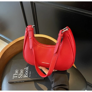 Detail of red lychee grain leather handbag with silver zipper on wooden stand