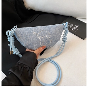 Détail d'un sac bandoulière en toile denim bleu clair avec broderie chien et bandoulière nouée