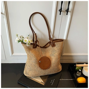 Detail of hand-woven straw tote bag with brown leather straps and summer vacation props