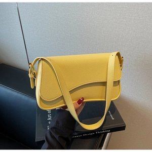 Close-up of yellow underarm bag with litchi grain leather and asymmetric flap