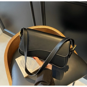 Gros plan d'un sac à bandoulière en cuir noir brillant avec boucle dorée et coutures