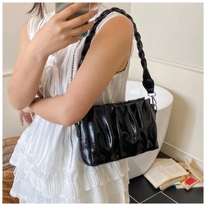 Detail of glossy black pleated crossbody bag with a thick woven chain shoulder strap