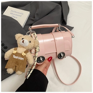 Pink cylinder handbag with silver buckle and cute bear charm in a lifestyle setting