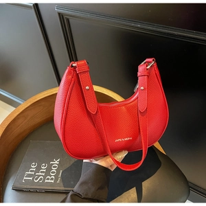 Detail of red crescent shoulder bag with lychee texture and silver metal hardware