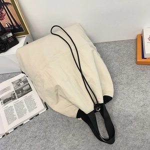 Detail der beigen Nylon-Kordelzugtasche mit schwarzen Riemen und verstellbaren Schnallen