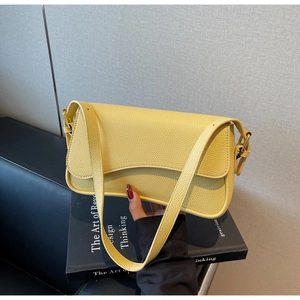 Detail of light yellow lychee pattern leather bag with gold hardware and flap closure