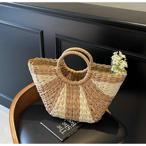 Detail view of woven straw tote bag with dual-tone fan pattern and golden thread edge
