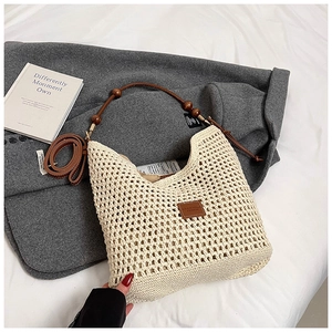 Detailed view of beige crochet tote bag with wooden bead straps and brown leather brand label