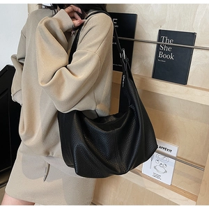 Detail of black pebbled leather hobo bag with adjustable strap shown on a model