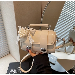 Dettaglio della borsa in pelle bianco crema con ciondolo a cuore di perle e fiocco