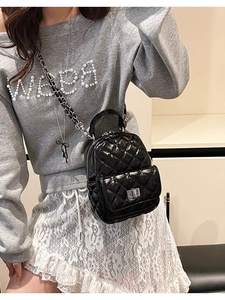 Quilted black patent leather mini backpack with silver twist lock on female model